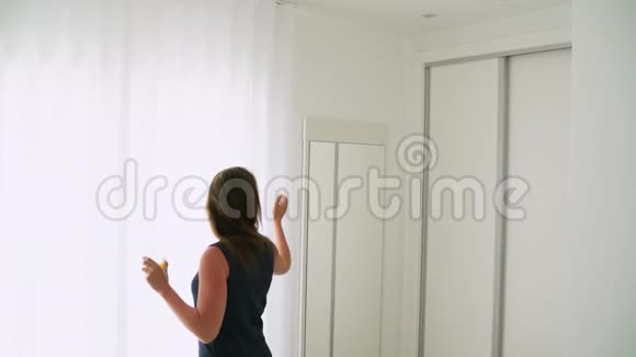 女人拉开卧室的窗帘慢慢地喝着橙汁视频的预览图