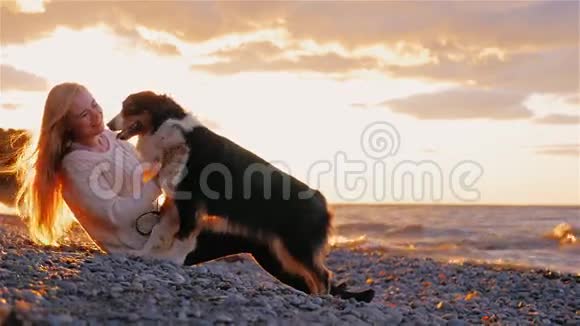 年轻女子在湖边或海边与澳大利亚牧羊犬玩耍视频的预览图