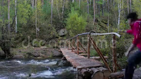 背着背包的女游客坐在横跨山河的木桥上视频的预览图
