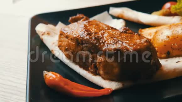 美味多汁的猪肉牛排配上土豆和蔬菜在餐厅的时髦黑色盘子里视频的预览图