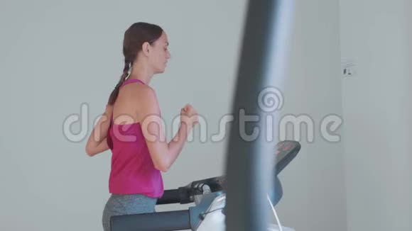 运动的年轻女子在跑步机上跑步后景特写视频的预览图