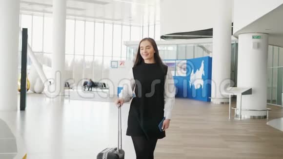 女游客在国际机场航站楼携带行李使用智能手机语音识别短信命令视频的预览图