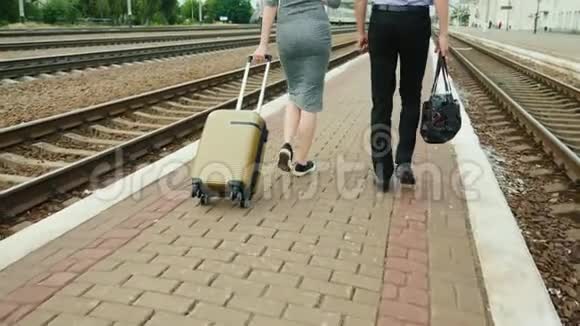两个带行李的商业伙伴正沿着铁路站台散步在框架中你只能看到腿视频的预览图