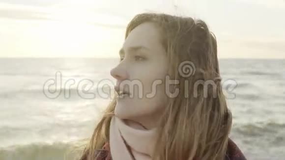 一幅年轻美丽的女人在海上眺望远方的肖像寒冷的日子里女人站在海滩上视频的预览图