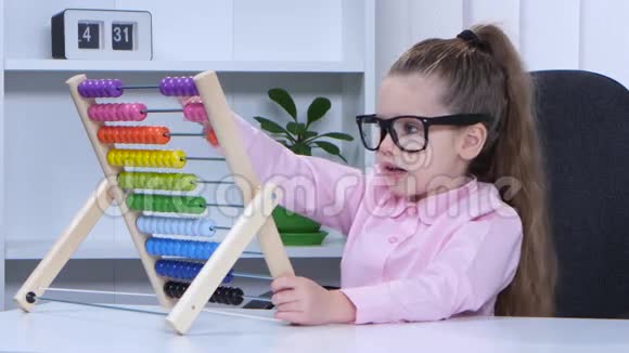 戴眼镜的小女孩坐在桌旁对五彩的账目说视频的预览图