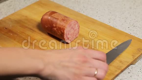 女性切片香肠在木板上女人用刀子在木板上割伤了她的手视频的预览图