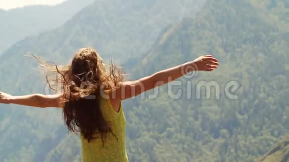 美丽的女人站在山顶伸出双手视频的预览图