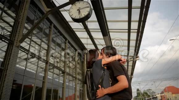 快乐的一对拥抱在火车站站台上在火车站告别年轻女孩和男人接吻视频的预览图