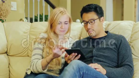 家和科技一对年轻夫妇喜欢平板电脑亚洲男人和高加索女人视频的预览图