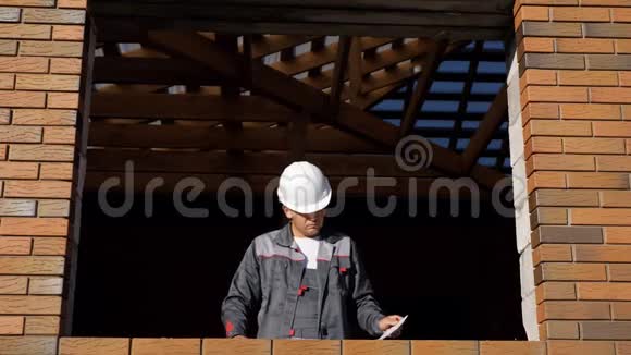 建筑工人站在正在建造的房屋的窗户上视频的预览图