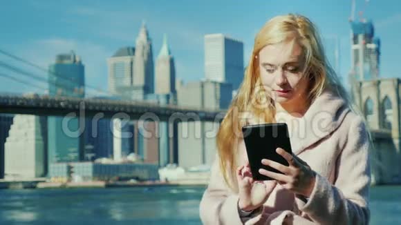 大城市的技术在布鲁克林大桥和曼哈顿的背景下享受盘子的年轻女子视频的预览图