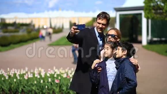 阳光明媚的一天快乐的一家人在公园的手机上自拍视频的预览图