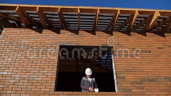 建筑工人站在正在建造的房屋的窗户上视频的预览图