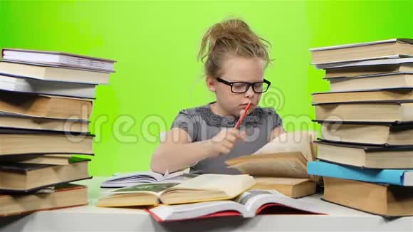小女孩坐在桌子旁紧张地扔书绿色屏幕慢动作视频的预览图