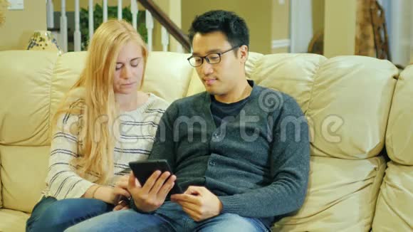 朋友韩国男人和高加索女人在家休息好好享受平板电脑吧视频的预览图