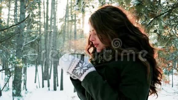 冬天在户外喝茶的漂亮女孩可爱的女孩拿着一个杯子从中冒出蒸汽年轻的女人喝茶视频的预览图