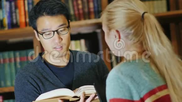 在大学学习在图书馆里微笑的亚洲男人奥斯查特西亚女人书架上放着书视频的预览图