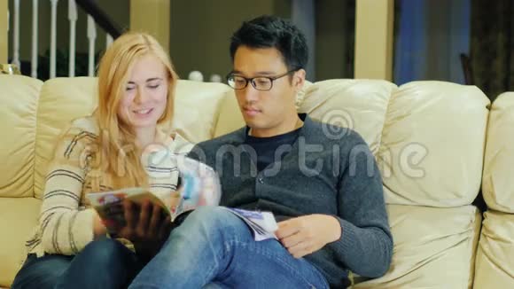 一起看杂志年轻的多民族夫妇呆在家里视频的预览图
