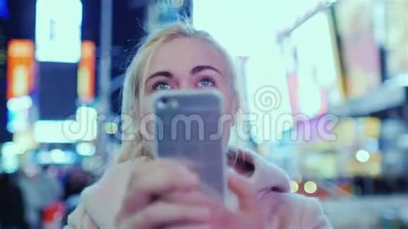 年轻女子欣赏纽约市著名的时代广场在电话里拍摄视频视频的预览图