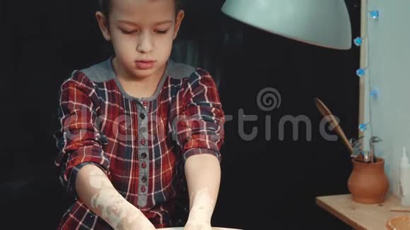 一个严肃的小女孩集中精力在制作陶轮上的陶器视频的预览图