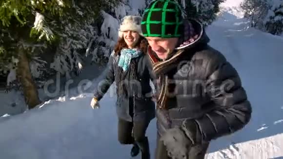 年轻的幸福家庭在雪林里玩得很开心父母把他们的小儿子卷在雪橇上慢动作视频的预览图