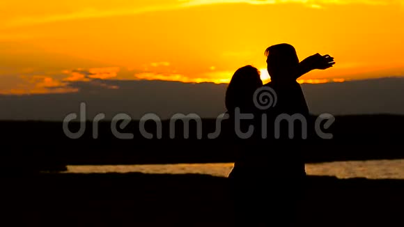 可爱的女孩和海滩上拥抱日落的男人视频的预览图