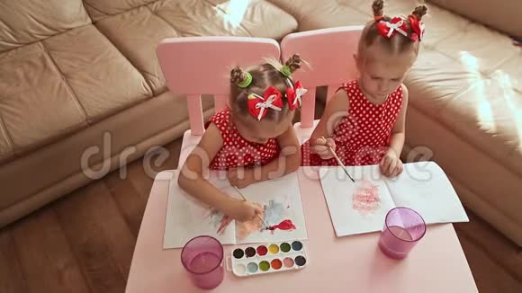 从上面看两个迷人的小妹妹双胞胎在纸上画水彩画坐在家里他们房间的一张桌子上视频的预览图