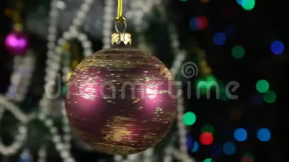 旋转一个红色的圣诞球和装饰圣诞树背景是闪烁的花环视频的预览图