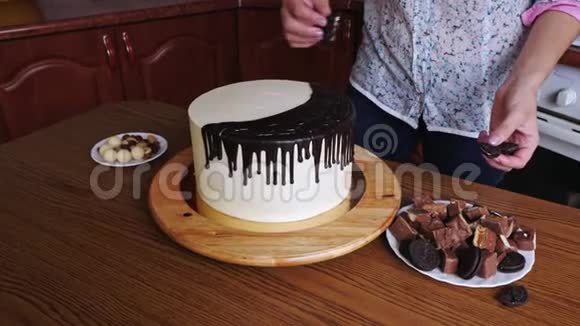 女人手的特写装饰一个蛋糕上面有巧克力和椒盐卷饼坚果视频的预览图