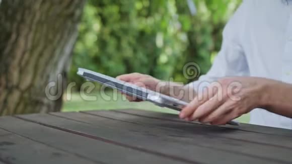 男人他的手在公园里用笔记本电脑视频的预览图