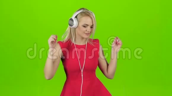 穿红色衣服的女孩戴着耳机跳舞戴着绿色屏幕视频的预览图
