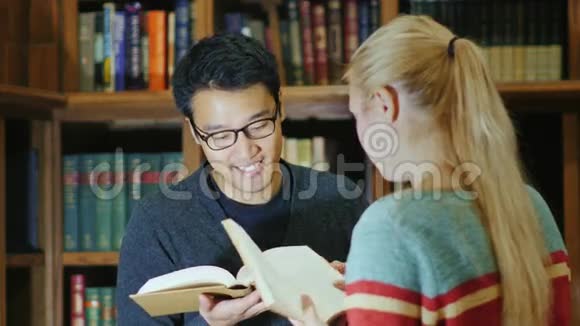 戴眼镜的韩国男人和一个女人在图书馆聊天视频的预览图