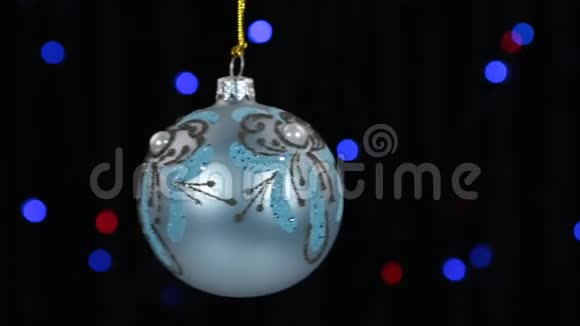 蓝色圣诞球摆动在离焦背景与闪烁的花环灯视频的预览图