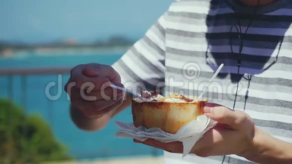 戴着太阳镜的人在椰子里吃水果冰淇淋和豆子在旅行时听音乐慢动作视频的预览图