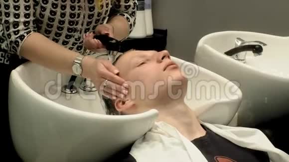 理发师在沙龙里给那个男头洗视频的预览图