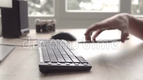 年轻人一边使用平板电脑一边坐着电脑键盘和鼠标自由职业者摄影师工作和使用平板电脑视频的预览图