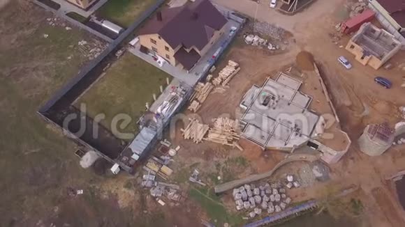 在新的现代化小屋附近正在进行的施工现场的鸟瞰图建筑材料和工人的浇筑视频的预览图