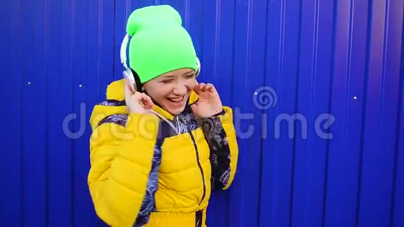 女孩带着耳机唱歌跳舞听音乐微笑快乐的女孩听耳机里的音乐视频的预览图