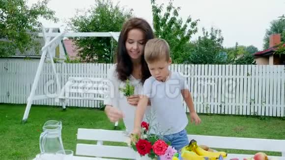 夏天在花园里妈妈和一个四岁的儿子做了一束花这个男孩非常喜欢它他很高兴视频的预览图