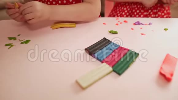 两个小女孩正在餐桌上做塑料成型手的儿童特写视频的预览图