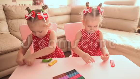 两个可爱的小双胞胎姐妹一起从事造型与多色塑料视频的预览图