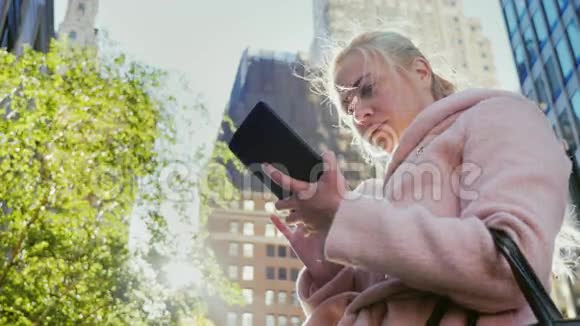 一个年轻的女人在城里使用平板电脑大都市视频的预览图