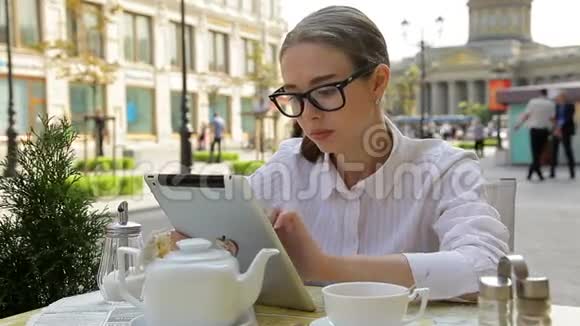 时尚的商务女性在街边的自助餐厅喝咖啡看电脑平板电脑视频的预览图