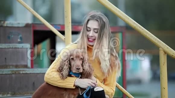 金发女人和狗公鸡西班牙猎犬抚摸狗关心亲吻微笑在城市的晚上视频的预览图