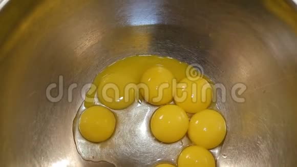 厨房柜台上的一个金属搅拌碗里的七个碎鸡蛋准备敲打或搅拌它们来烘烤视频的预览图