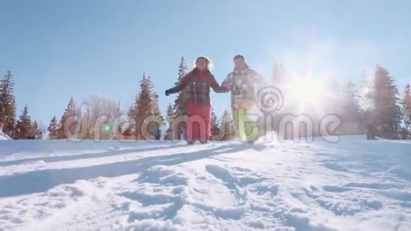 明亮的阳光冬天的季节快乐的年轻人牵着他们的手在雪地里滑着摔倒了快乐地摔倒了视频的预览图