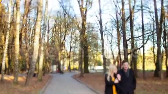 婴儿镜头观看美丽的夫妇走在秋天的城市公园的手臂笑和亲吻对方城市视频的预览图