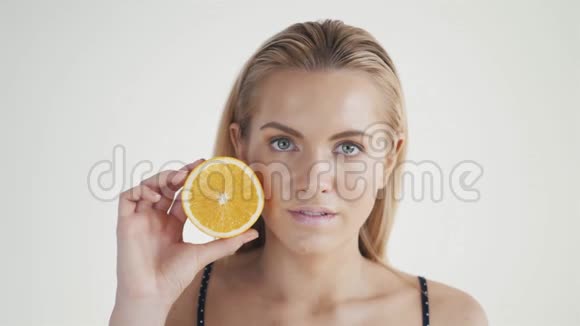 健康生活方式的好食物美丽的年轻无衫金发女子眼前捧着一块橘子视频的预览图