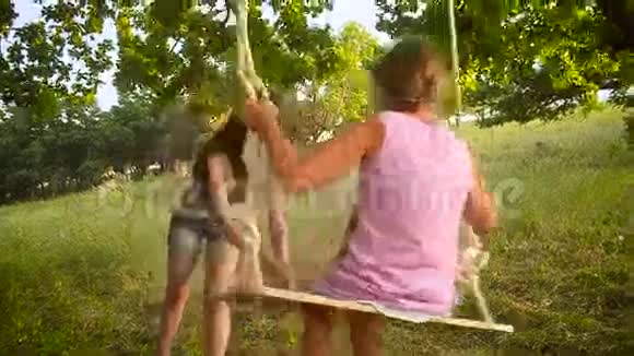 快乐的妈妈摇着她的小女孩在公园里荡秋千视频的预览图