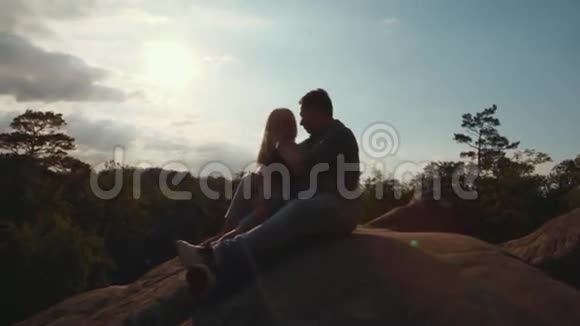一对年轻夫妇在岩石的顶端英俊的年轻情人在明亮的阳光下温柔地抚摸着他的女朋友视频的预览图